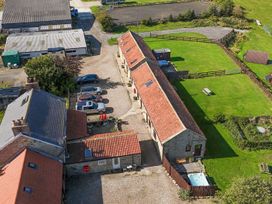 An outdoor area with multiple buildings and vehicles at Woodpeckers Shepherds hut in Staintondale near Burniston