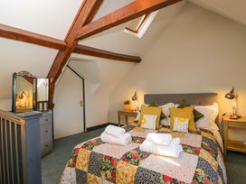 A bedroom with a bed and mirror at Elm Cottage Moreton-In-Marsh