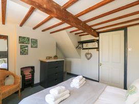 A bedroom with a bed, mirror and dresser at Elm Cottage Moreton-In-Marsh