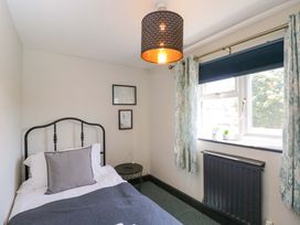 A bedroom with a bed and side table at Elm Cottage in Moreton-In-Marsh
