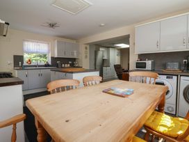 A kitchen with a wooden dining table and chairs with yellow cushions a microwave toaster washing machine and fridge at 4 Queen Street in Withernsea