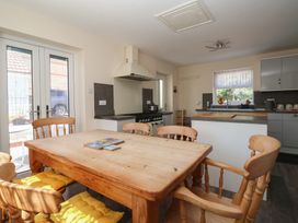 A kitchen with wooden dining table and chairs yellow cushions stove and sink by window at 4 Queen Street in Withernsea