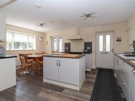 A kitchen with a central island, wooden dining table and chairs, and white cabinets at 4 Queen Street in Withernsea