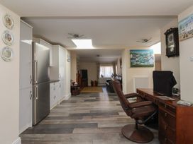 An open plan kitchen and living area with a stainless steel fridge desk with office chair and wall clock at 4 Queen Street in Withernsea