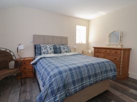 A bedroom with a bed with blue plaid bedding a wooden dresser with a mirror a wicker chair and a wooden nightstand with a lamp at 4 Queen Street in Withernsea
