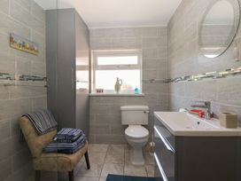 A bathroom with a toilet a sink with storage a window a chair with towels and a tall cabinet at 4 Queen Street in Withernsea