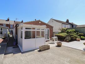 A backyard with a small white conservatory attached to a brick building with outdoor furniture and potted plants at 4 Queen Street in Withernsea