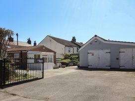 An outdoor area with a black metal gate two small buildings with white doors and a concrete driveway at 4 Queen Street in Withernsea
