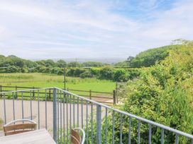 A view from a balcony overlooking a grassy field and trees at The Cottage in St. Ives