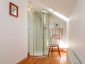 A bathroom with a shower and a chair at The Cottage St. Ives