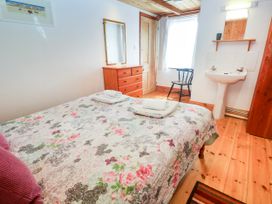 A bedroom with a bed and dresser at The Cottage in St. Ives