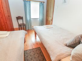 A bedroom with two beds and a chair at The Cottage in St. Ives