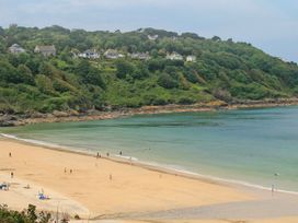 A beach with people walking and houses on a hillside at The Cottage in St. Ives