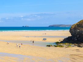 A beach with people walking and playing near water at The Cottage in St. Ives