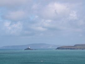 A lighthouse on an island in the ocean with clouds at The Cottage in St. Ives