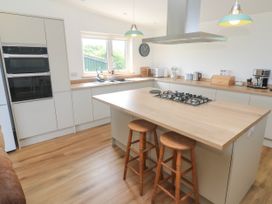 A kitchen with a stove and bar stools at Swallows Nest in St. Ives