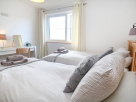 A bedroom with two beds and a desk at Swallows Nest in St. Ives