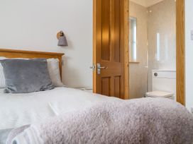 A bedroom with a bed and a bathroom in view at Swallows Nest in St. Ives