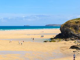 A beach with people and a rocky cliff at Swallows Nest in St. Ives