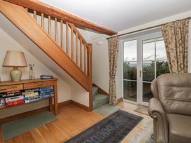 A living room with a staircase and board games on the table at Wren Cottage in Ross-on-Wye