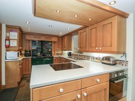 A kitchen with wooden cabinets and appliances at Wren Cottage in Ross-on-Wye