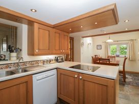 A kitchen with wooden cabinets and dining table at Wren Cottage in Ross-on-Wye