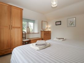 A bedroom with two beds and a wardrobe at Wren Cottage in Ross-on-Wye