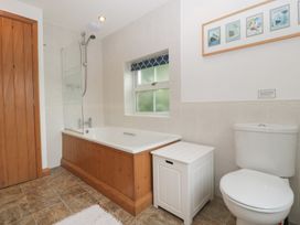 A bathroom with a bath, shower, toilet, and window at Wren Cottage in Ross-on-Wye