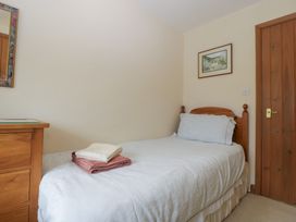 A bedroom with a single bed and wooden furniture at Wren Cottage in Ross-on-Wye