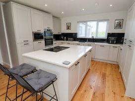 A kitchen with cabinets and an island at Rose Cottage Dunstan near Embleton