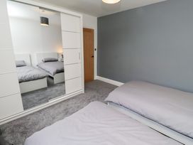 A bedroom with beds and wardrobe at Rose Cottage Dunstan near Embleton