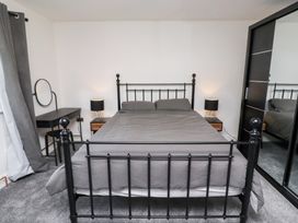 A bedroom with a bed, nightstand, lamp and desk at Rose Cottage in Dunstan near Embleton