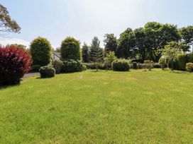 A garden with grass and various bushes at Rose Cottage Dunstan near Embleton