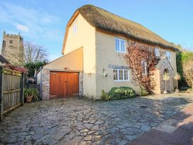 A house with a thatched roof stone driveway and garage near a church at Church Thatch in Abbotskerswell