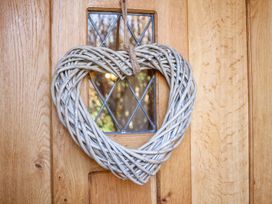 A heart-shaped wicker wreath hanging on a wooden door with a glass window at Church Thatch in Abbotskerswell