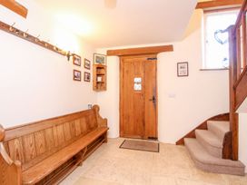 An entryway with a wooden bench coat rack wooden door and carpeted stairs at Church Thatch in Abbotskerswell