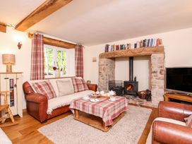 A living room with a fireplace sofa and coffee table with teacups at Church Thatch in Abbotskerswell