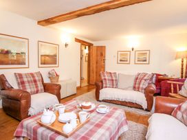 A living room with leather sofas and a table set with tea and cake at Church Thatch in Abbotskerswell