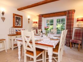 A dining room with a table set for six and plaid curtains at Church Thatch Abbotskerswell