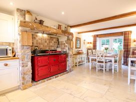 A kitchen with a red stove and dining table with chairs near windows at Church Thatch in Abbotskerswell