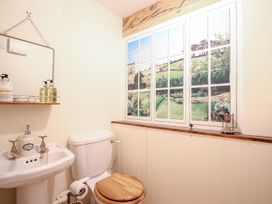 A bathroom with a sink a toilet and a painted window mural at Church Thatch in Abbotskerswell