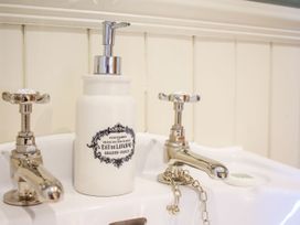 A bathroom sink with silver taps and a white soap dispenser at Church Thatch in Abbotskerswell