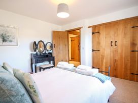 A bedroom with a bed towels on it a black vanity table with mirror wooden doors and a framed picture on the wall at Church Thatch in Abbotskerswell
