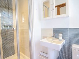A bathroom with a shower, sink, mirror cabinet, and toilet at Church Thatch in Abbotskerswell