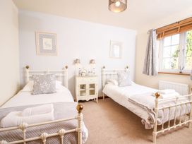 A bedroom with two single beds and a window at Church Thatch in Abbotskerswell