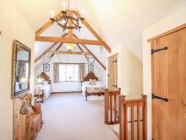A bedroom with two single beds wooden beams exposed ceiling and wooden doors at Church Thatch in Abbotskerswell