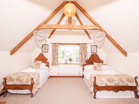 A bedroom with two single beds under a sloped ceiling with wooden beams at Church Thatch in Abbotskerswell