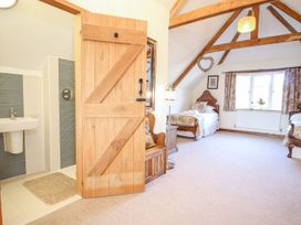 A bedroom with two single beds a wooden door leading to a bathroom and exposed ceiling beams at Church Thatch in Abbotskerswell