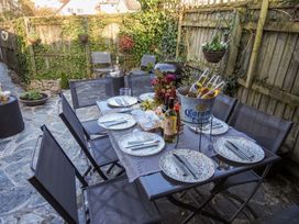 An outdoor dining area with a table set with plates knives glasses a flower centerpiece and a bucket of Corona beers at Church Thatch in Abbotskerswell