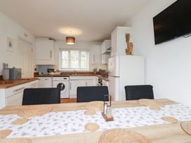A kitchen with appliances and dining table at Poldam St Austell
